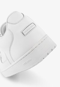 Fehér bőr sneaker, sima felülettel, párnázott bokával és gumitalppal, az oldalán "PEGAJOR" felirattal.