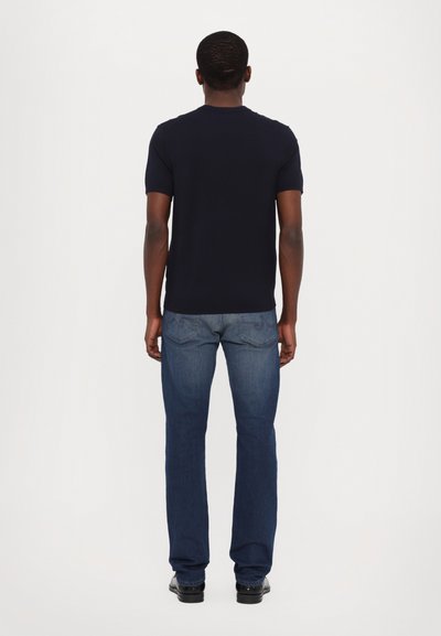 Marineblauw T-shirt met korte mouwen, gecombineerd met donkerblauwe denim jeans met een rechte pijp en eenvoudige stikdetails.