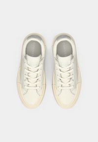 Un paio di sneakers bianche low-top Converse All Star pulite, con suole beige e lacci bianchi, viste dall'alto su uno sfondo semplice.