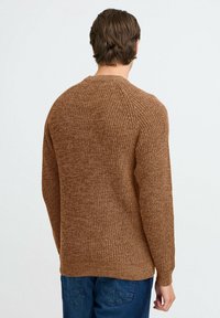 Brązowy sweter dzianinowy z teksturowanym wzorem, ściągaczami przy mankietach i u dołu. Projekt zawiera rękawy raglanowe dla luźnego dopasowania.