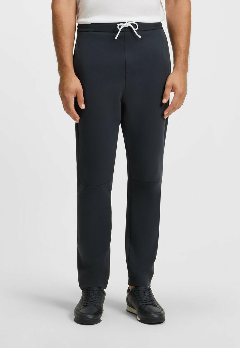 Marina joggers i stretchigt tyg med dragsko i midjan, med slim fit och sidofickor. Kombineras med svarta sneakers.