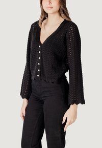 Gilet en tricot noir avec un col en V, des manches longues en forme de cloche et un ourlet festonné. Présente une fermeture par boutons en argent et un motif texturé.