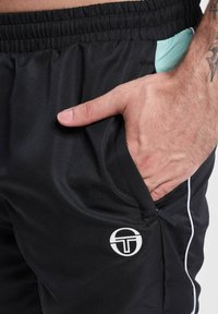 Shorts atletici negri cu un finisaj texturat, dotati cu un buzunar lateral, accente contrastante de culoare albastru deschis și un logo alb pe partea inferioară a piciorului.