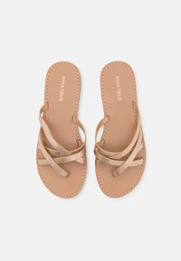 Sandali beige con cinturini incrociati, dotati di una finitura testurizzata. Soletta liscia con bordi cuciti. Nome del brand "ANNA FIELD" impresso.