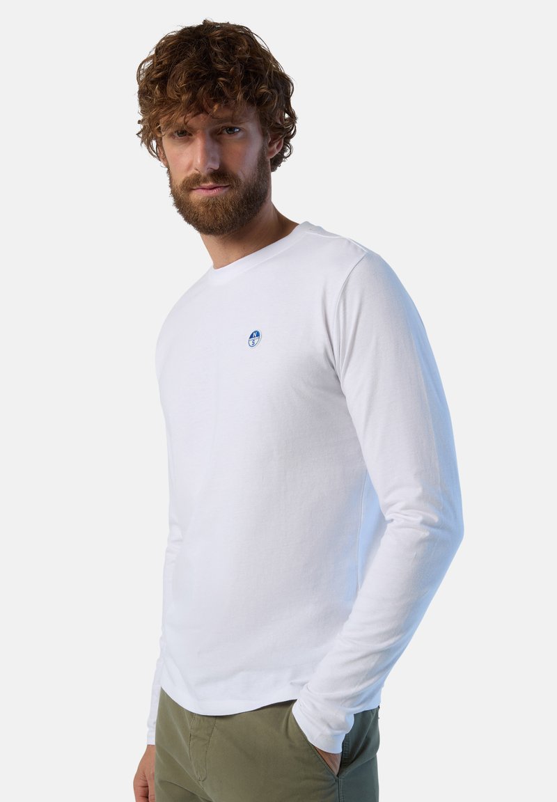 T-shirt a maniche lunghe bianco in cotone, con un piccolo logo blu sul petto. Design semplice, vestibilità rilassata con scollo rotondo.