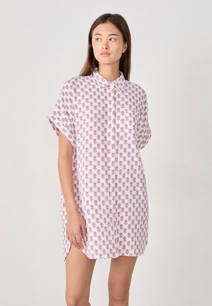 Abito camicia a maniche corte in cotone bianco, con un motivo floreale rosa, colletto e spacchi laterali per facilitare i movimenti.
