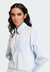 Prúžkovaná bunda na zips v svetlomodrej a bielej farbe, s golierom, elastickými manžetami a predným vreckom s malým logom.