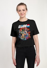 Czarna koszulka z kolorową grafiką G.I. Joe przedstawiającą wiele postaci. Projekt zawiera wyraziste kolory i szczegółowe ilustracje.