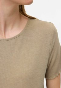 Camiseta de rayas de color marrón claro con escote redondo y mangas cortas. La tela tiene una textura suave, con un ligero estiramiento y detalles de costura visibles.