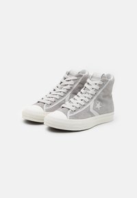 Gray high-top sneakers made of suede, featuring a rubber toe cap, white laces, and a star accent on the side. Subtle texture detail visible.