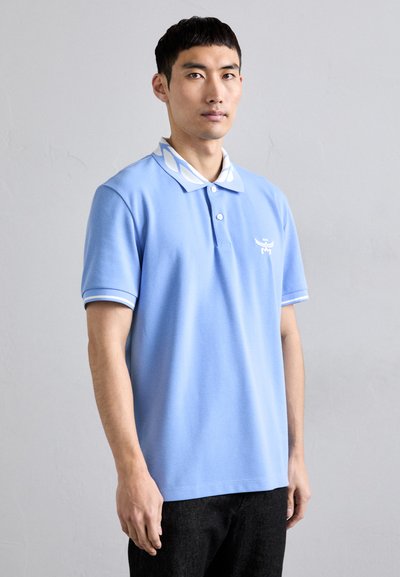 Polo shirt bleu clair avec un col et des poignets à motifs blancs. Présente un petit logo brodé sur la poitrine gauche.