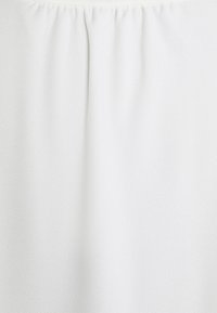 Tissu à ceinture élastique blanche avec une texture subtile et des fronces, suggérant un matériau de vêtement extensible.