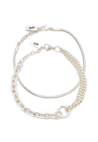 Dvoje prepletených strieborných náramkov s karabínkovými zapínaniami a malými obdĺžnikovými visačkami s vyrytým podpisom.