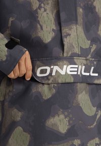 O'Neill kamufliažinė striukė su tekstūruotu tamsiai pilku ir žaliu raštu, ryškiu baltu logotipu ir Velcro uždarymo detale.