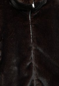 Jakna od tamnoljubičaste umjetne krzno sa visokim ovratnikom, prednjim patentnim zatvaračem i mekanom, teksturiranom površinom. Glatki završetak sa blagim sjajem.