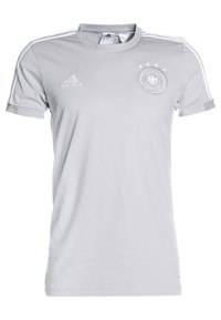 Šedý sportovní dres s krátkým rukávem a bílými akcenty. Obsahuje loga, včetně kulatého emblému a tří hvězdiček nahoře. Vyrobeno z lehkého materiálu.