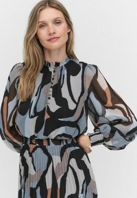 Langärmlige Bluse aus transparenter Stoff mit abstraktem Muster in Blau, Schwarz und Beige, mit Knöpfen an der Vorderseite und einem gerafften Bund.