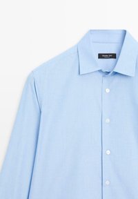 Lichtblauwe button-up overhemd met een klassieke kraag, gemaakt van een soepele stof, met een subtiele textuur en witte knopen aan de voorkant.