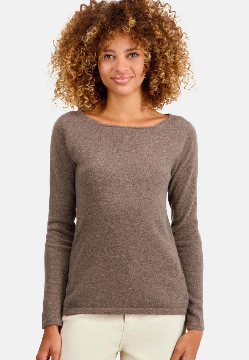 Pull marron à manches longues avec un grand col, texture douce et design ajusté, associé à un pantalon clair.