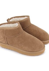 Botas de tobillo de ante marrón con un suave forro de piel blanca. Suela de goma con agarre texturizado y diseño cosido a lo largo de los bordes.