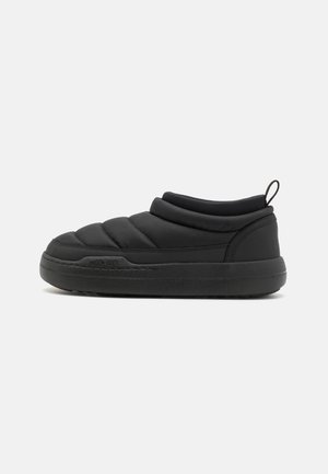 Scarpa slip-on nera imbottita con punta rotonda, suola in gomma spessa e dettagli cuciti. Progettata per il comfort con una texture morbida.
