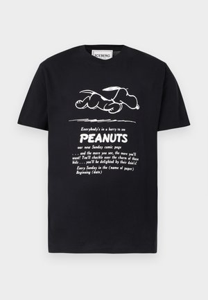 Fekete póló fehér vázlattal Snoopy fekvés közben, és szöveg, amely az új Peanuts vasárnapi képregényoldalt hirdeti.