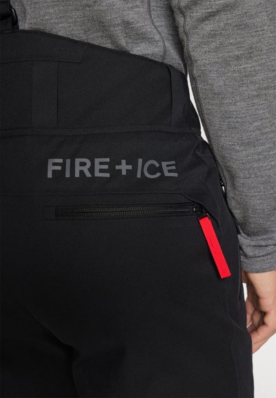 Μαύρες φόρμες με λεία υφή, που διαθέτουν τσέπη με φερμουάρ και κόκκινο τραβηχτάρι φερμουάρ. Το όνομα της μάρκας "FIRE + ICE" είναι ευδιάκριτα εκτυπωμένο.