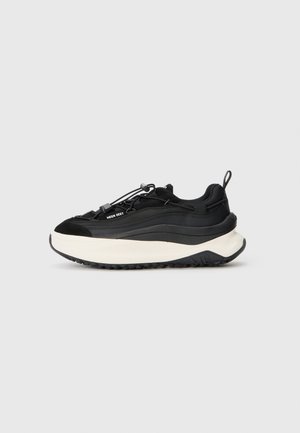 Schwarze Sneakers mit einem strukturierten Wildleder- und glatten Synthetik-Obermaterial, einer dicken weißen Zwischensohle und einer robusten schwarzen Außensohle mit einer Schlaufe.