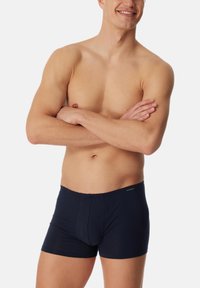 Boxer shorts da uomo di un blu navy scuro realizzati in tessuto morbido, con un design aderente, apertura frontale e senza pattern o accenti visibili.
