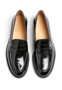 Schwarze Lacklederloafer mit runder Zehenpartie, dekorativer Naht und einer niedrigen Gummisohle. Das Innere ist mit einem hellbraunen Lederfutter ausgestattet.