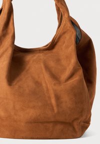 Bruine suède handtas met een zachte textuur, met een slonzig ontwerp en een brede opening. Merkennaam is aan de onderkant geperst.