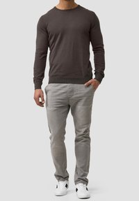 Gray knitted pullover with long sleeves, round neckline, paired with light gray slim-fit pants and white sneakers with black accents.
