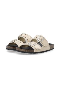 Beige slipper sandalen met zilveren gespaccenten, ronde vorm, geperforeerde bovenkant voor ademend vermogen, en een gestructureerde zwarte buitenzool voor grip.
