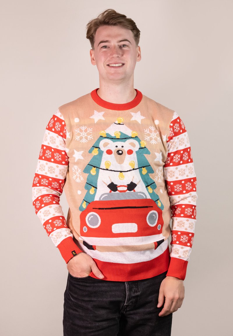 Roter und beigefarbener Pullover mit einem Bären, der einen Weihnachtsbaum und Lichter fährt, in einem roten Auto. Dekorative Schneeflockenmuster an den Ärmeln.