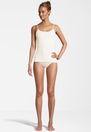Camisola beige chiaro con spalline sottili, design aderente, texture morbida e silhouette senza cuciture, abbinata a un'intimo beige chiaro coordinato.