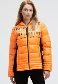 Padded jacket in bright orange with black accents, featuring a zip closure and printed text designs on the front. Smooth texture, hooded.