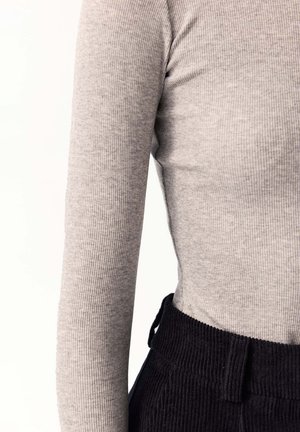 Szary prążkowany longsleeve połączony z czarnymi spodniami z korduroju o teksturowanej tkaninie i dopasowanej talii.