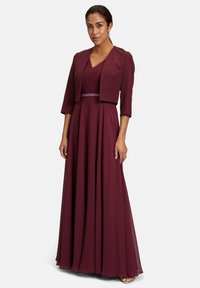Bordeaux maxi-jurk met een geplooide bustier, V-hals en korte bolero-jack. Glad stof en een subtiele, bewerkte riem als accent.