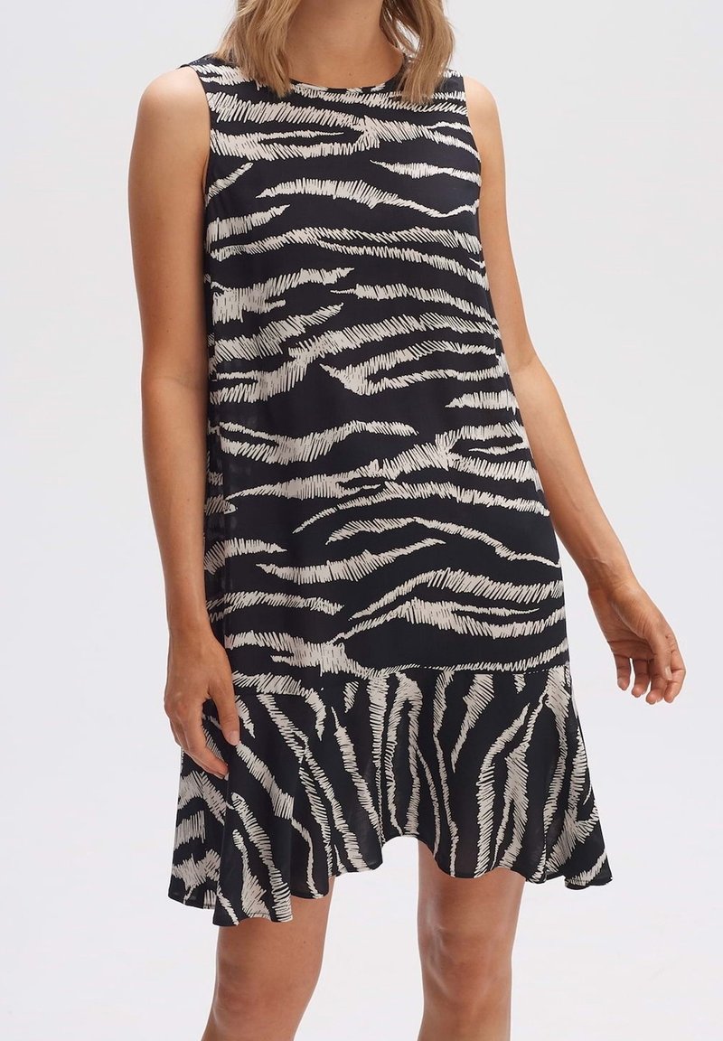 Bezramenné černobílé šaty se zigzagovým zebrovaným vzorem, ve tvaru A, s mírně rozšířeným lemem pro snadný pohyb.