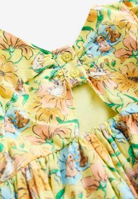 Blumenkleid mit gelbem Hintergrund und orangefarbenen sowie blauen Blumen. Der Ausschnitt hat einen Knopfverschluss und eine geraffte Taillenstruktur.