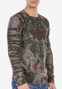 Langarm-T-Shirt in Grau mit roten Spritzern und grafischem Design, das einen Adler und Text zeigt, aus weichem Baumwollmischgewebe hergestellt.