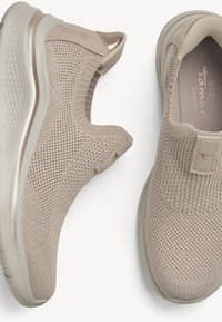 Baskets légères beige clair à enfiler avec dessus en maille tricotée, semelle coussinée et détail métallique sur la languette du talon, vues de dessus et de côté.