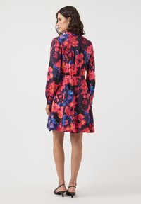 Black dress with red, pink, and blue floral print, featuring long sleeves and an elastic waist, ending above the knees. A smooth texture.