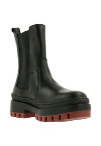 Black leather ankle boot with elastic side panels, chunky rubber platform sole in red and black, and stitched detailing along the edge.