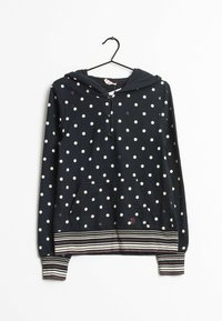 Sudadera azul marino con lunares blancos, botones en la parte delantera, puños y dobladillo a rayas, y un bolsillo frontal, colgada de una percha negra.
