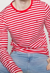 Rød- og hvidstribet langærmet t-shirt med rund hals og lille logo på brystet, lavet af blødt bomuldsstof.