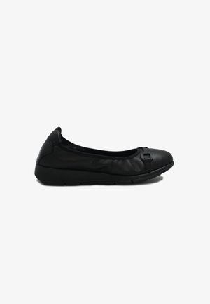 Scarpa piatta senza lacci in pelle nera con punta arrotondata e sottile dettaglio decorativo a fiocco sulla parte anteriore, caratterizzata da una suola leggermente rialzata.