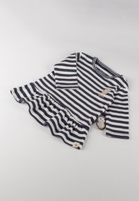 Marineblau- und weiß gestreiftes Langarmoberteil mit ausgestellt geschnittenem Saum, einem Eulenmotiv und einem dekorativen Eulenanhänger an der Seite. Hergestellt aus weichem Stoff.