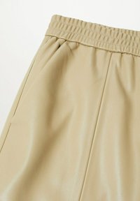 Beige neplederen shorts met een elastische tailleband, zijzakken en een zachte textuur met een subtiele glans.