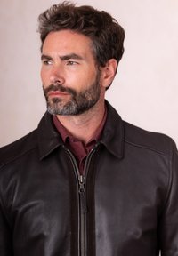 Brown leather jacket with a zip closure, standing collar, and contrasting black accents. Worn over a maroon shirt, smooth texture.